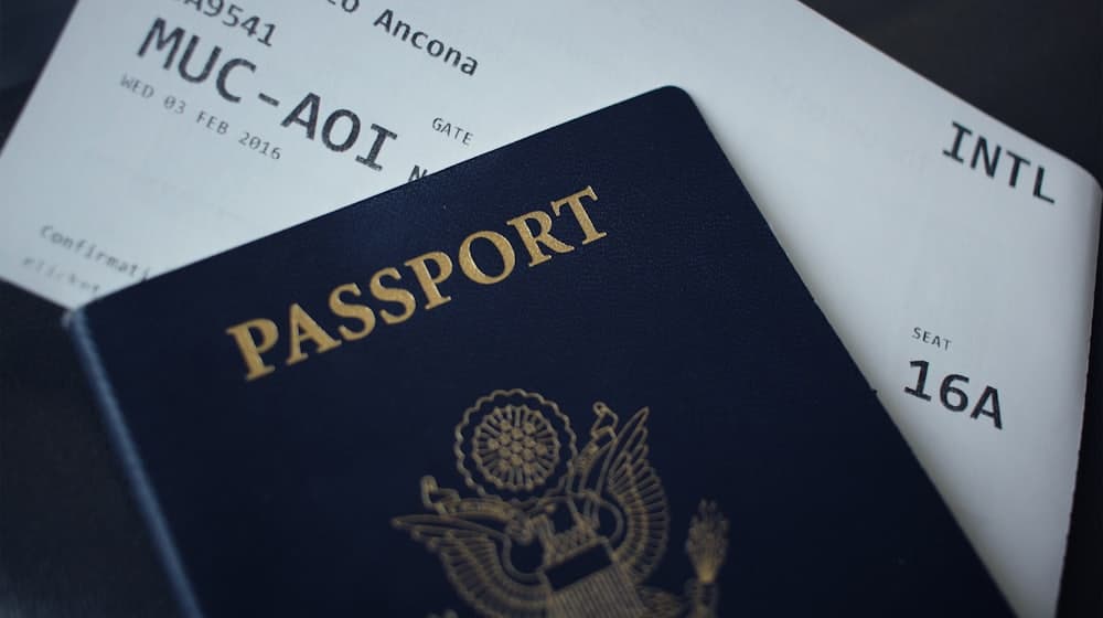 A navy passport lying across two printed boarding passes on a dark desk.